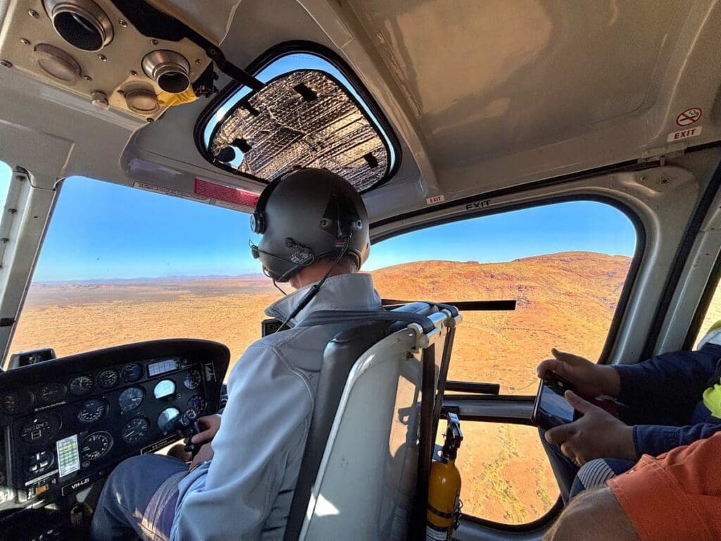 ACHM staff performing an aerial survey from inside a helicopter.